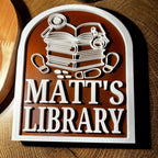 Custom bookshelf sign with stack of books, detective icons, and text 'Matt's Library'