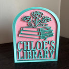 Personalized library sign with teal books and roses on pink background, custom book decor