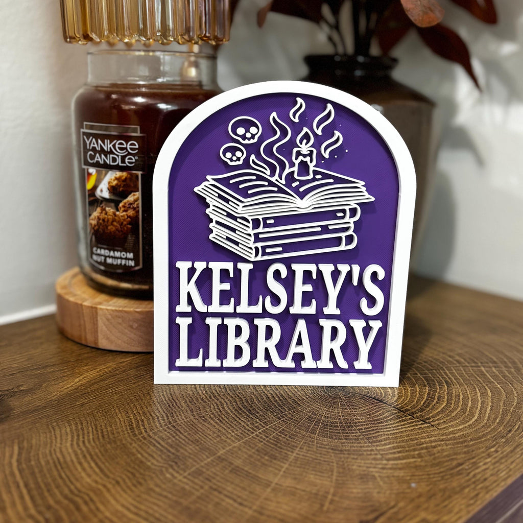 Personalized library sign with books, candle, and skulls on a purple background for book nook decor