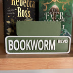 Back of the small green sign behind the large BOOKWORM BLVD street sign
