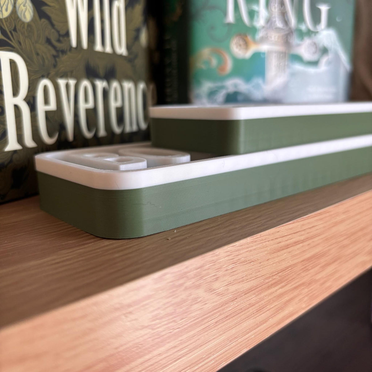 Side profile of the olive green and white BOOKWORM BLVD street signs lying flat