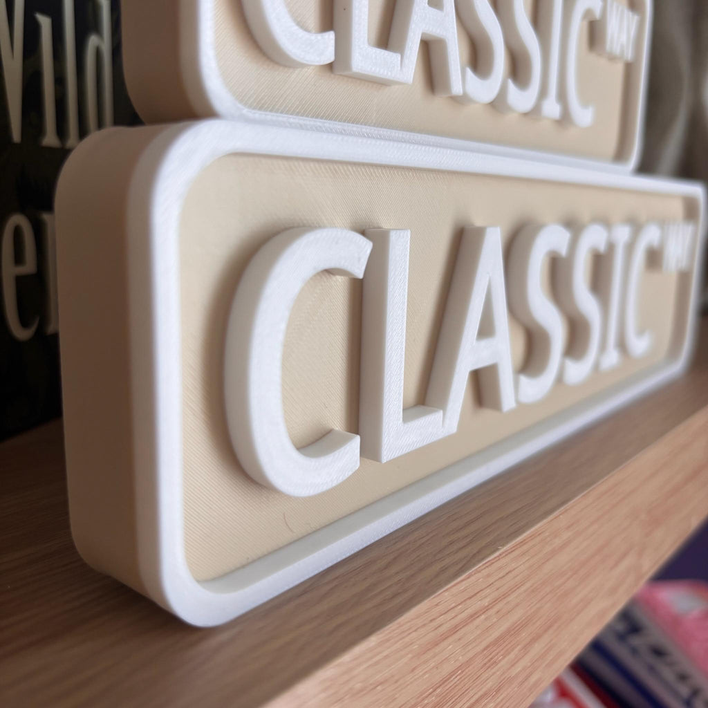 Close angled view of the raised white lettering on the beige CLASSIC WAY street sign