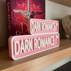 Front view of the pink DARK ROMANCE DR street signs in front of a fantasy book