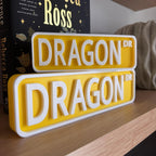 Yellow and white DRAGON DR street signs, small stacked on large, on a bookshelf