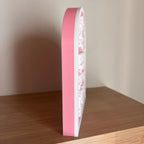 Side view of the pink and white Fictional Boyfriends arched sign standing on its own on a shelf