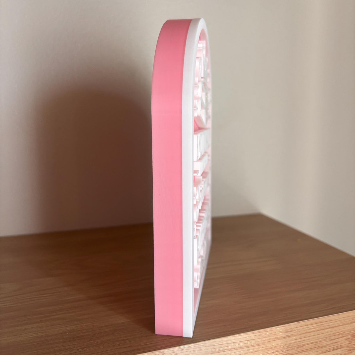 Side view of the pink and white Fictional Boyfriends arched sign standing on its own on a shelf