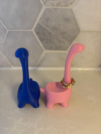 Two dinosaur-shaped ring holders, one blue and one pink. The pink dinosaur has a gold ring on its neck. __etsy:6791612930