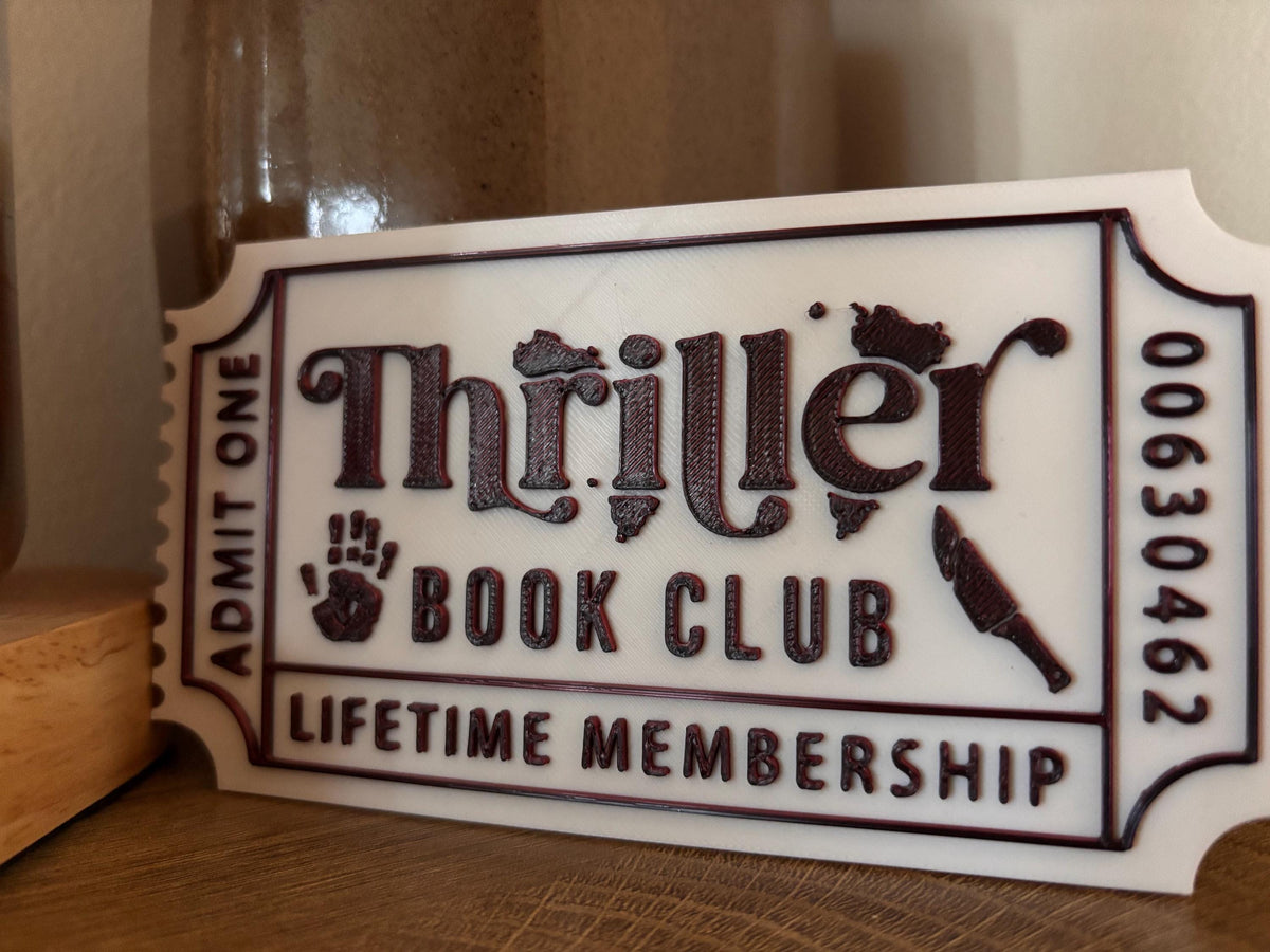 Angled view of the white Thriller Book Club ticket with black lettering