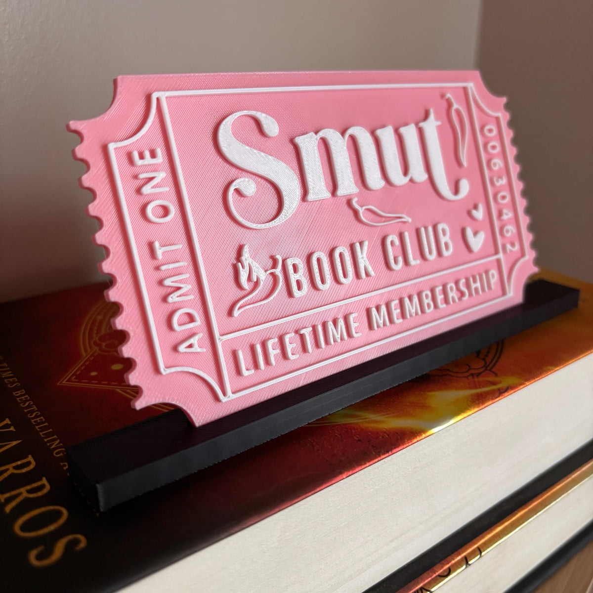 Pink Smut Book Club ticket with white lettering in a black stand